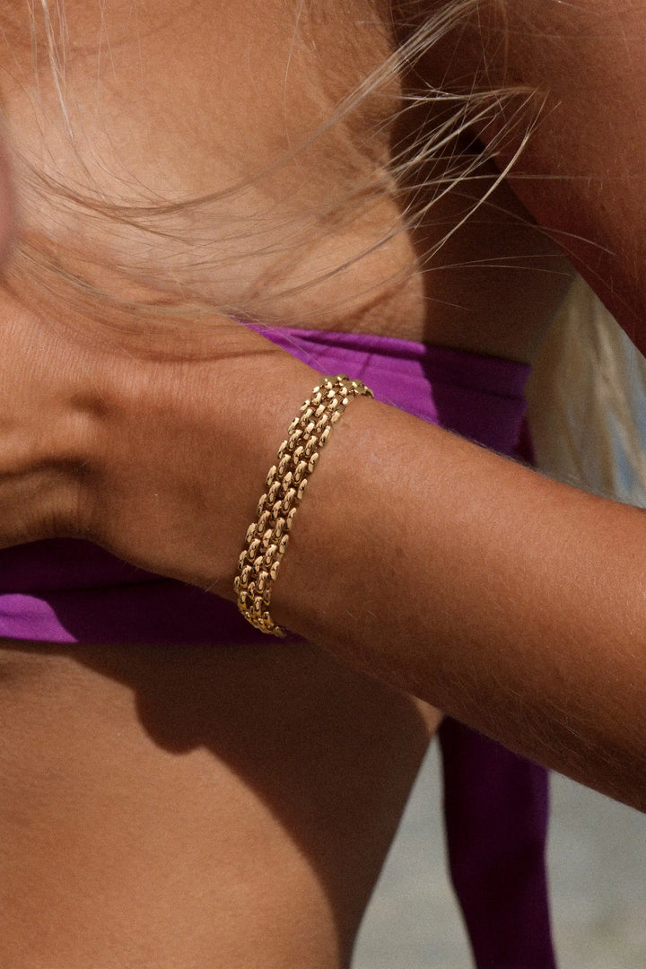 Gold chain bracelet on a wrist with a blurred background